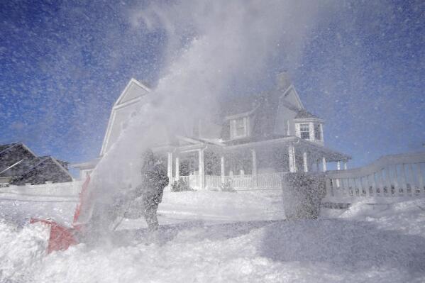 Bill McKelvey, of Scituate, Mass., uses a snow blower to clear snow in front of his home, Sunday, Jan. 30, 2022, in Scituate. (AP Photo/Steven Senne)