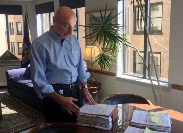 
              In this Aug. 7, 2018, photo, Mark Robbins, the last remaining member of the Merit Systems Protection Board, looks through stacks of legal cases piled up on his desk in Washington off...