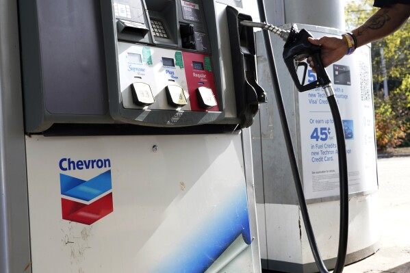 A customer replaces the pump dispenser at a Chevron gas station in Columbus, Miss., Monday, Oct. 23, 2023. Chevron is buying Hess Corp. for $53 billion as major producers seize the initiative while oil prices surge. (AP Photo/Rogelio V. Solis)