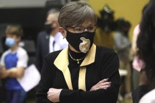 In this Monday, May 17, 2021, photo,  Kansas Gov. Laura Kelly tours a COVID-19 vaccination clinic for students aged 12 through 15 set up in a gym at Topeka High School in Topeka, Kan. The Democratic governor is under increasing pressure to end an extra $300 a week in benefits for unemployed workers, with critics of the aid arguing that businesses are having problems hiring enough workers because of it. (AP Photo/John Hanna)