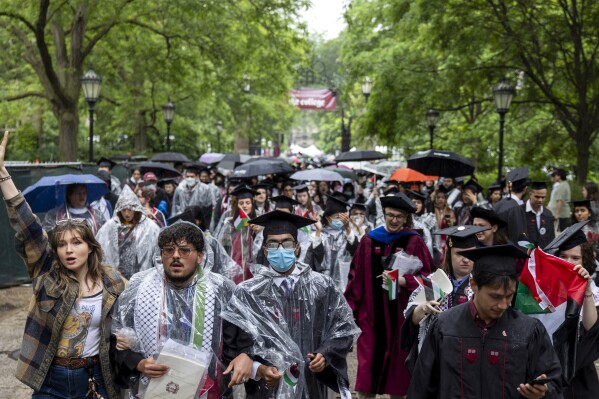 University of Chicago students, including Youssef Hasweh, second from left, one of four students the university is withholding degrees from due to their involvement in an encampment, walk out of the university's convocation ceremony in support of Palestinians on Saturday, June 1, 2024, in Chicago. (Vincent Alban/Chicago Tribune via AP)