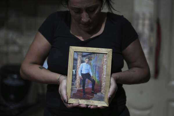 Claudia Caballero poses with a photo of her late son Alexis Almiron, a cancer patient who tried to get medication that had been covered by federal agency DADSE, but which President Javier Milei dissolved, in the outskirts of Buenos Aires, Argentina, Monday, May 5, 2025. (AP Photo/Natacha Pisarenko)