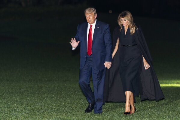 President Donald Trump, accompanied by first lady Melania Trump, waves as he walks from Marine One on the South Lawn of the White House, early Friday, Oct. 23, 2020, in Washington. Trump is returning from a debate in Nashville, Tenn. (AP Photo/Alex Brandon)