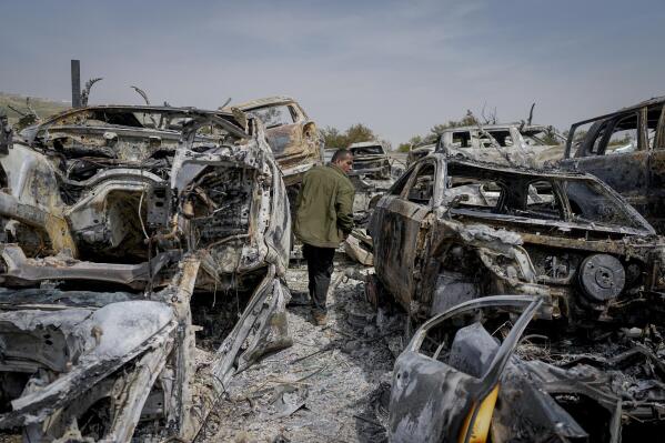 A Palestinian man walks between scorched cars in a scrapyard, in the town of Hawara, near the West Bank city of Nablus, Monday, Feb. 27, 2023. Scores of Israeli settlers went on a violent rampage in the northern West Bank, setting cars and homes on fire after two settlers were killed by a Palestinian gunman. Palestinian officials say one man was killed and four others were badly wounded. (AP Photo/Ohad Zwigenberg)
