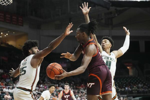 Virginia Tech forward Justyn Mutts (25) attempts to pass the ball between Miami guard Jordan Miller (11) and forward Norchad Omier (15) during the first half of an NCAA college basketball game, Tuesday, Jan. 31, 2023, in Coral Gables, Fla. (AP Photo/Marta Lavandier)