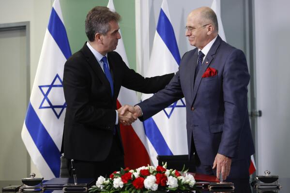 Poland's Minister of Foreign Affairs Zbigniew Rau, right, and his Israeli counterpart Eli Cohen, left, shake hands after signing an agreement allowing the resumption of Israeli youth trips to Poland in Warsaw, Poland, Wednesday, March 22, 2023. (AP Photo/Michal Dyjuk)