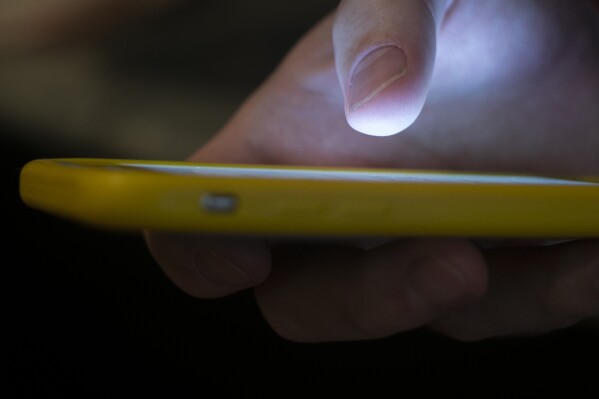 FILE - A man uses a cell phone in New Orleans on Aug. 11, 2019. Some social media users are calling out celebrities for what they say is inaction in the face of a humanitarian crisis in Gaza — and they've taken to a "blockout" to pressure the stars to take a stand. For the blockout, users put a block on seeing any and all content from the accounts of certain celebrities on social media platforms including X, TikTok and Instagram. (Ǻ Photo/Jenny Kane, File)