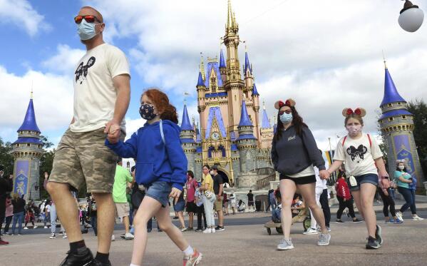 FILE - In this Dec. 21, 2020, file photo, a family walks past Cinderella Castle in the Magic Kingdom, at Walt Disney World in Lake Buena Vista, Fla. (Joe Burbank/Orlando Sentinel via AP, File)