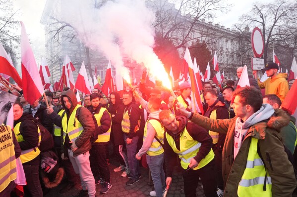 Polish farmers with national flags and angry slogans written on boards protest against European Union green policies that trim their production and against cheap grain and other food imports from Ukraine, in Warsaw, Poland, on Tuesday, Feb. 27, 2024. Farmers have been protesting for weeks across the EU. (AP Photo/Czarek Sokolowski)