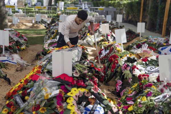 Liyam, 20, first name given, pays respects at the grave of his fellow commander, at Mount Herzl military cemetery, in Jerusalem, on Monday, Oct. 16, 2023. (AP Photo/Petros Giannakouris)