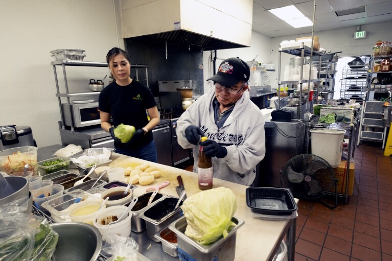 Anna Le Nguyen, and Minh Rasavong Oriyavong help out in the kitchen of "Love & Thai" in Fresno, Calif. on Wednesday, Dec. 20, 2023. The Thai restaurant, is back in operation after being wrongfully accused of abusing a dog to turn it into meat. It may be astonishing to some that a claim rooted in a racist stereotype took down a restaurant three years after "Stop Asian Hate" became a rallying cry. (AP Photo/Richard Vogel)