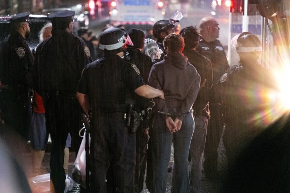 As light rain falls, New York City police officers take people into custody near the Columbia University campus in New York, Tuesday, April 30, 2024, after a building taken over by pro-Palestinian protesters earlier in the day was cleared, along with a tent encampment. (AP Photo/Craig Ruttle, File)