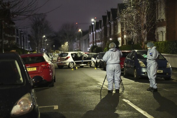Police inspect the scene of an incident near Clapham Common, south London, after a suspected corrosive substance was thrown at a woman and her two young children Wednesday Jan. 31, 2024. British police said Wednesday they are hunting for a suspect after several people were injured with a corrosive substance in London.(James Weech/PA via AP)