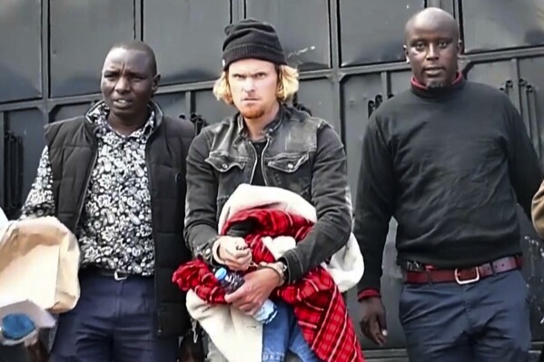 In this picture taken from video New Zealand's Olympic runner Zane Robertson, center, is arrested at his home in Iten, Kenya, Wednesday, Sept. 20, 2023. Police obtained a court order to hold Robertson in custody for five working days while they question him and investigate. He appeared in court on Thursday for a short hearing and police said that he would be charged after the investigations are completed. (AP Photo/KASS TV)