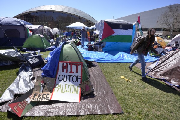 A passer-by, right, walks through an encampment of tents, Thursday, April 25, 2024, on the Massachusetts Institute of Technology campus, in Cambridge, Mass. Students at MIT set up the encampment of tents on the campus to protest what they said was MIT's failure to call for an immediate ceasefire in Gaza and to cut ties to Israel's military. (AP Photo/Steven Senne)