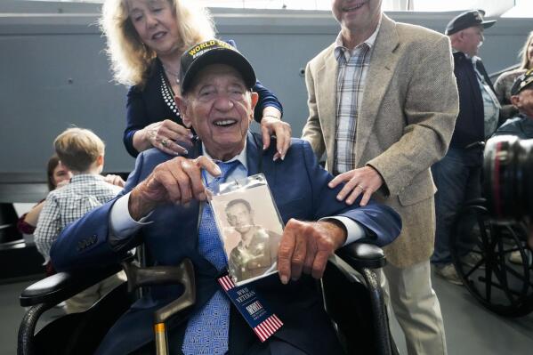 World War II veteran Joseph Eskenazi, who at 104 years and 11 months old is the oldest living veteran to survive the attack on Pearl Harbor, holds a photo of his younger self, at an event celebrating his upcoming 105th birthday at the National World War II Museum in New Orleans, Wednesday, Jan. 11, 2023. (AP Photo/Gerald Herbert)