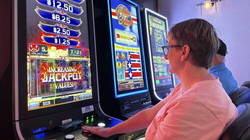 Gabi Mosbrucker, of Bismarck, plays electronic pulls tabs at the Bismarck AMVETS in Bismarck, N.D,, Wednesday, July 5, 2023. North Dakota's attorney general announced, Thursday, July 6, 2023, a settlement with three gambling equipment distributors he accused in April of violating the state's charitable gambling laws. The settlement comes amid disagreements and confusion surrounding issues related to electronic pull tab machines, which have proliferated in North Dakota since 2018. (AP Photo/Jack Dura)