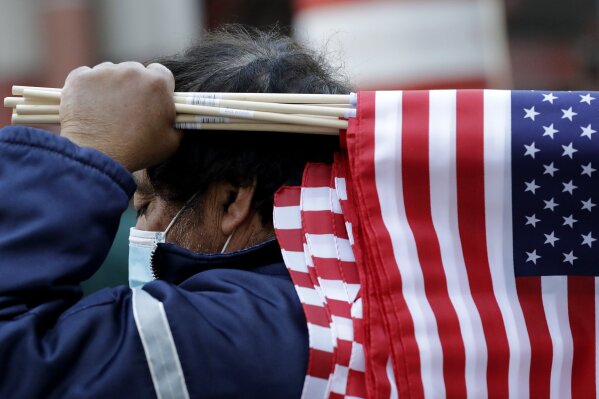 A street vendor sells American flags during a rally against Illinois stay-at-home order outside the Thompson Center in downtown Chicago, Friday, May 1, 2020. The Friday demonstration is the latest in a series of protests around the country against stay-at-home orders designed to slow the spread of the coronavirus. (AP Photo/Nam Y. Huh)