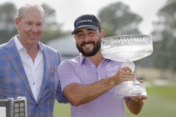 Jim Crane, left, owner of the Houston Astros baseball team, and Stephan Jaeger pose for photos with the trophy during ceremonies after Jaeger's win after the final round of the Houston Open golf tournament Sunday, March 31, 2024, in Houston. (AP Photo/Michael Wyke)