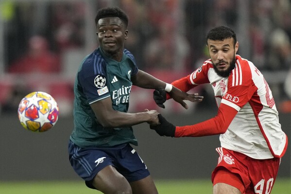Bayern's Noussair Mazraoui, right, challenges Arsenal's Bukayo Saka during the Champions League quarter final second leg soccer match between Bayern Munich and Arsenal at the Allianz Arena in Munich, Germany, Wednesday, April 17, 2024. (AP Photo/Matthias Schrader)