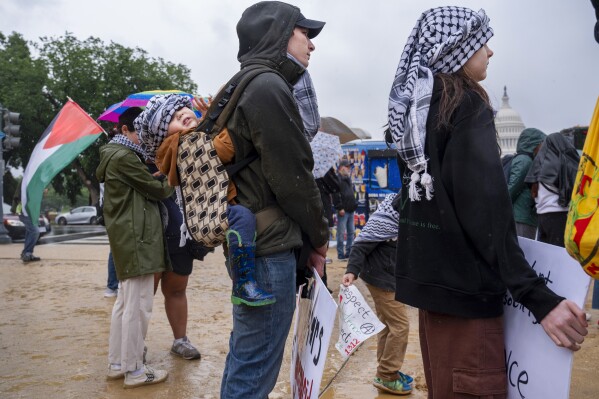 Cody Wolfe, center, of Elizabethtown, Penn., holds his two-year old son on his back wearing a keffiyeh, as he and his children attend a pro-Palestinian rally, Saturday, May 18, 2024, on the National Mall near the Capitol in Washington. "For our family it's the least we can do," says Wolfe, who said he is not of Palestinian descent but has been attending protests, "to show our solidarity. We want the babies to stop dying." (AP Photo/Jacquelyn Martin)