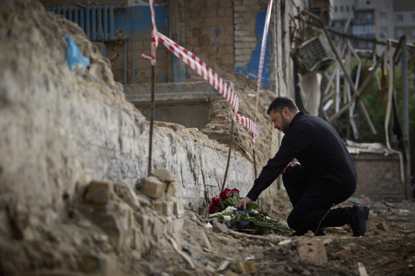 In this photo provided by the Ukrainian Presidential Press Office, Ukrainian President Volodymyr Zelenskyy lays flowers at the site of Russia's Tuesday deadly missile attack that ruined a multistory residential building in Kyiv, Ukraine, Thursday, June 19, 2025. (Ukrainian Presidential Press Office via AP)