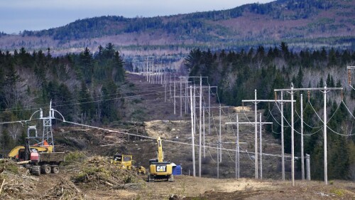 FILE - Heavy machinery is used to cut trees to widen an existing Central Maine Power power line corridor to make way for new utility poles, April 26, 2021, near Bingham, Maine. Developers of a project aimed at bringing hydropower from Canada to the New England power grid are trying to sort out how cost increases that occurred during lengthy litigation will be shared. (AP Photo/Robert F. Bukaty, File)