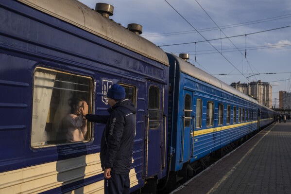 Ruslan Mishanin, 36, right, bids farewell to his nine year old daughter as the train with his family leaving for Poland, at the train station in Odesa, Monday, April 4, 2022. (AP Photo/Petros Giannakouris)
