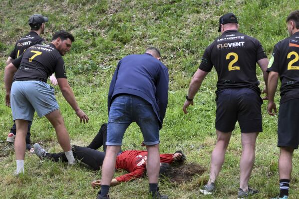 A participant rests after the women's downhill race of the traditional annual Cheese Rolling contest at Cooper's Hill in Brockworth, Gloucestershire, England, Monday, May 26, 2025.(AP Photo/Anthony Upton)