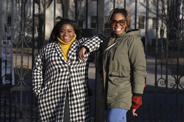 Chassity Coston, left, and Charity Wallace pose outside Harvard Yard at Harvard University, Saturday, Feb. 24, 2024, in Cambridge, Mass. With attacks on diversity, equity and inclusion initiatives raging on, Black women looking to climb the work ladder are seeing a landscape that looks more hostile than ever. (AP Photo/Michael Dwyer)