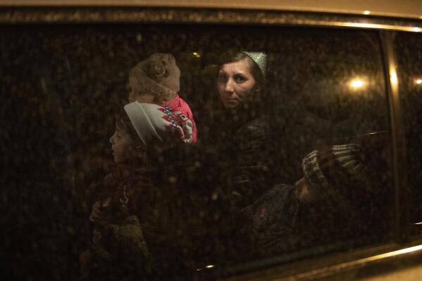 A woman from Ukraine with her children sit in a car belonging to a volunteer, to take them to a hostel after arriving at Keleti station in Budapest, Hungary, on Friday, March 18, 2022. (AP Photo/Anna Szilagyi)