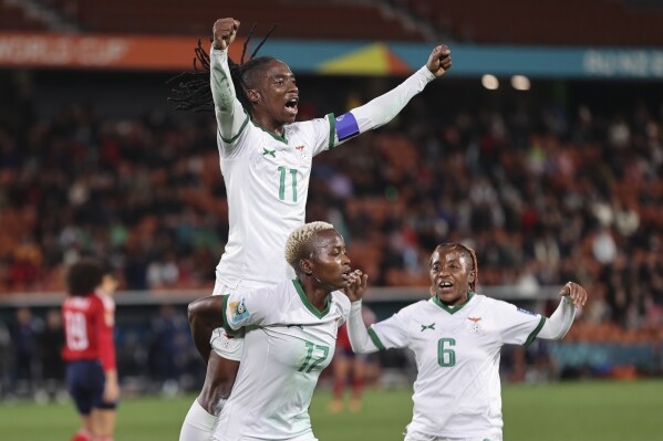 Goal scorer Zambia's Racheal Kundananji carries teammate Barbra Banda as Mary Wilombe, right, runs in as they celebrate their third goal during the Women's World Cup Group C soccer match between Costa Rica and Zambia in Hamilton, New Zealand, Monday, July 31, 2023. (AP Photo/Juan Mendez)