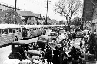This 1942 photo shows the evacuation of American-born Japanese civilians during World War II, as they leave their homes for internment, in Los Angeles, California. The sidewalks are piled high with indispensable personal possessions, cars and buses are waiting to transport the evacuees to the war relocation camps. (AP Photo)