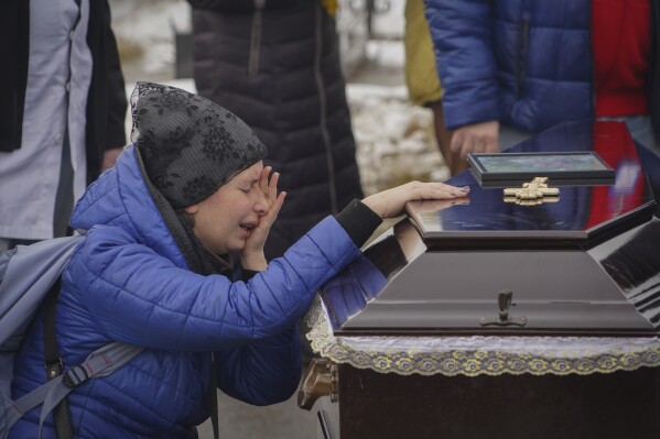 People mourn over the coffins of a family killed in a fire when Russian drone hit their home in residential neighbourhood in Kharkiv, Ukraine, Monday, Feb. 12, 2024. Seven people including three children were killed on Saturday in the Russian drone attack. (APPhoto/Andrii Marienko)