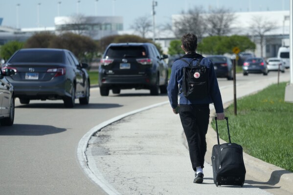 A passenger walks on the highway as he carries his luggage to at O'Hare International Airport in Chicago, Monday, April 15, 2024. Pro-Palestinian demonstrators blocked a freeway leading to three Chicago O'Hare International Airport terminals Monday morning, temporarily stopping vehicle traffic into one of the nation's busiest airports and causing headaches for travelers. (AP Photo/Nam Y. Huh)