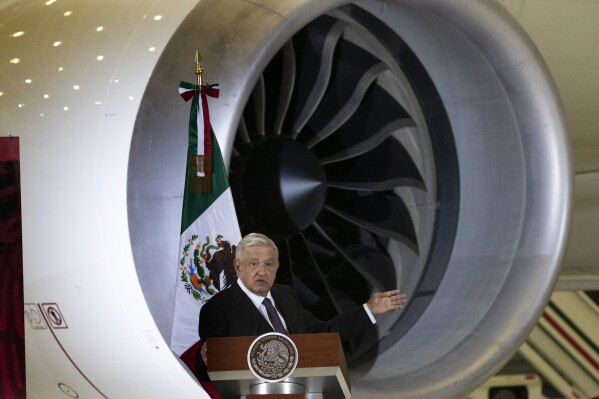 FILE - Mexican President Andres Manuel Lopez Obrador gives his daily, morning press conference in front of the former presidential plane at Benito Juarez International Airport in Mexico City, July 27, 2020. Mexico has announced its army-run airline will start up in September 2023, but flight attendants won’t be soldiers. The administration of President Andrés Manuel López Obrador has also put trains, tourism and infrastructure projects under the army's command. (AP Photo/Marco Ugarte File)