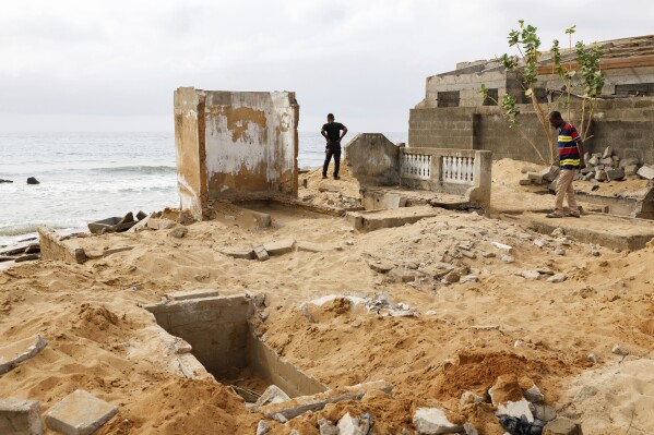 Some residents visit the family cemetery of Afeli Bernice Adzo, where remains were exhumed due to coastal erosion in Avegadzi, Ghana, Wednesday, March 5, 2025 (AP Photo/Misper Apawu)