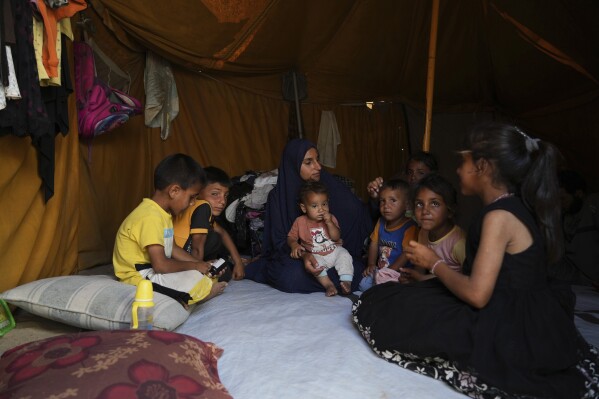 Maryam Abu Shaar, 29, sits with her children inside their tent at a camp for displaced Palestinians in Mawasi Khan Younis, Gaza Strip, on the first day of Eid al-Adha, Friday, June 6, 2025. (AP Photo/Abdel Kareem Hana)