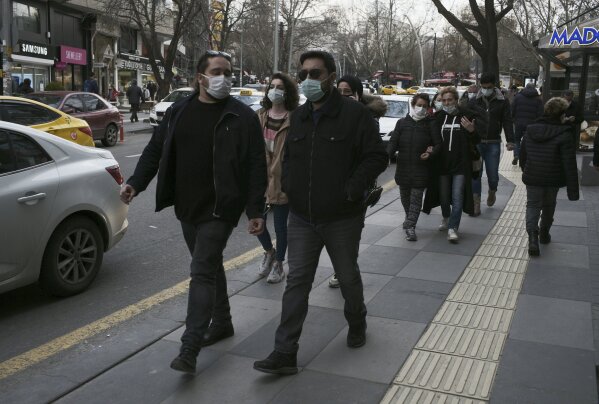 People wearing masks to help protect against the spread of coronavirus, walk in Ankara, Turkey, Monday, March 29, 2021. Turkey is reinstating weekend lockdowns in most of Turkey's provinces and will also impose restrictions over the Muslim holy month of Ramadan following a sharp increase in COVID-19 cases.(AP Photo/Burhan Ozbilici)