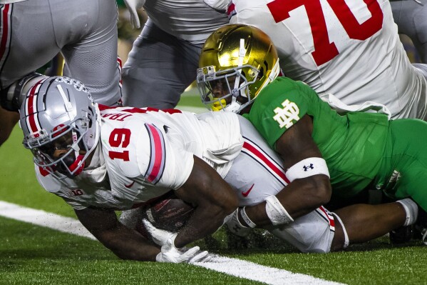 Ohio State running back Chip Trayanum (19) scores as Notre Dame safety DJ Brown (2) tries to stop him during the second half of an NCAA college football game Saturday, Sept. 23, 2023, in South Bend, Ind. (AP Photo/Michael Caterina)