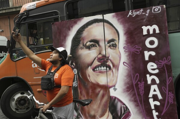 A supporter of presidential candidate Claudia Sheinbaum takes a selfie with a campaign poster during Sheinbaum's closing campaign rally at the Zocalo in Mexico City, Wednesday, May 29, 2024. (AP Photo/Matias Delacroix)