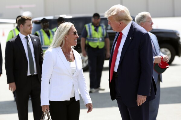 FILE - Former President Donald Trump is greeted by Rep. Majorie Taylor Greene, R-Ga., as he arrives at Atlantic Aviation CHS in North Charleston, S.C., Monday, Sept. 25, 2023. With five days to go before a government shutdown, Congress returns to work in crisis mode. Green said she would be a “hard no” on the vote to open debate, known as the Rule, because the package of bills continues to provide at least $300 million for the war in Ukraine. (AP Photo/Artie Walker Jr., File)
