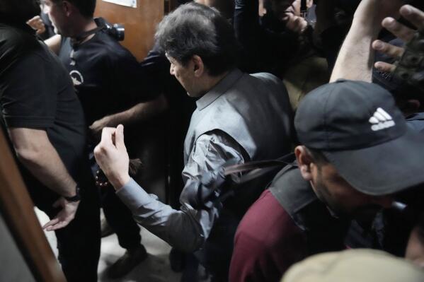 Former Prime Minister Imran Khan, center, leaves after appearing in a court, in Lahore, Pakistan, Tuesday, March 21, 2023. A Pakistani court on Tuesday granted Khan a weeklong bail in two cases in which he faces terrorism charges, officials said. The ruling gave the embattled ousted premier and now popular opposition leader another brief reprieve from arrest. (AP Photo/K.M. Chaudary)