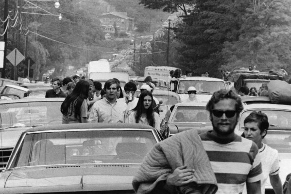FILE - In this Aug. 15, 1969 file photo, concert goers abandon their trucks, cars and buses as thousands try to reach the Woodstock Music and Art Festival at White Lake in Bethel, N.Y. Although Arlo Guthrie famously announced from the festival stage that "The New York State Thruway is closed, man," that wasn't exactly the case. Police closed at least one thruway exit east of the festival to stem the source of a blockbuster traffic jam around the site. The New York Daily News reported on Aug. 16 that cars were being delayed by as much as eight hours between New York City and the concert site - a distance of less than 100 miles.  (AP Photo)