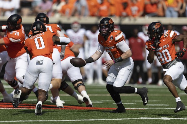 Oklahoma State quarterback Alan Bowman (7) hands the ball off to running back Ollie Gordon II (0) during the first half of an NCAA college football game against Arkansas, Saturday, Sept. 7, 2024, in Stillwater, Okla. (AP Photo/Mitch Alcala)