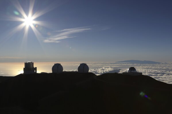 The sun sets behind telescopes at the summit of Mauna Kea, Hawaii's tallest mountain, Sunday, July 14, 2019. Hundreds of demonstrators gathered at the base of Hawaii's tallest mountain to protest the construction of a giant telescope on land that some Native Hawaiians consider sacred. State and local officials will try to close the road to the summit of Mauna Kea Monday morning to allow trucks carrying construction equipment to make their way to the top. Officials say anyone breaking the law will be prosecuted. Protestors have blocked the roadway during previous attempts to begin construction and have been arrested. (AP Photo/Caleb Jones)