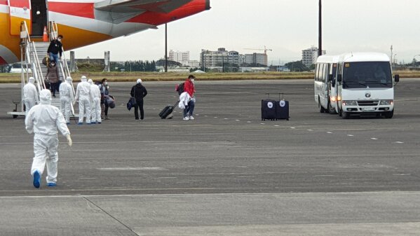 In this handout photo released by the Department of Foreign Affairs, men in protective suits check repatriated Filipinos as they arrive on a chartered flight at Clark air base, Pampanga province, northern Philippines on Sunday Feb 9, 2020. A charter flight carrying Filipinos from Wuhan, the city at the center of the outbreak, arrived in the Philippines. The 29 adults and one infant will be quarantined at New Clark City for 14 days, the virus's incubation period. (Department of Foreign Affairs via AP)