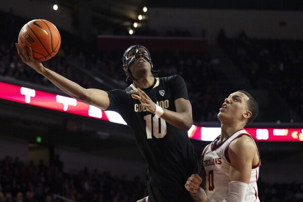 Colorado forward Cody Williams (10) shoots next to Southern California guard Kobe Johnson (0) during the second half of an NCAA college basketball game Saturday, Feb. 17, 2024, in Los Angeles. Colorado won, 92-89 in double overtime. (AP Photo/Kyusung Gong)