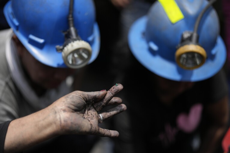 A female miner holds a fleck of an emerald on her fingertip, while working at an informal mine near the town of Coscuez, Colombia, Thursday, Feb. 29, 2024. Older villagers said that men previously barred women from approaching the mines because they believed that if women were around, the emeralds would hide. (AP Photo/Fernando Vergara)