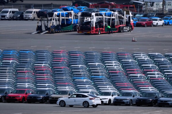 Workers, back, unload vehicles while a car, center front, is moved to another location of the area, where export vehicles are parked at the Daikoku vehicle terminal center in Yokohama, near Tokyo, April 8, 2025. (AP Photo/Hiro Komae, File)